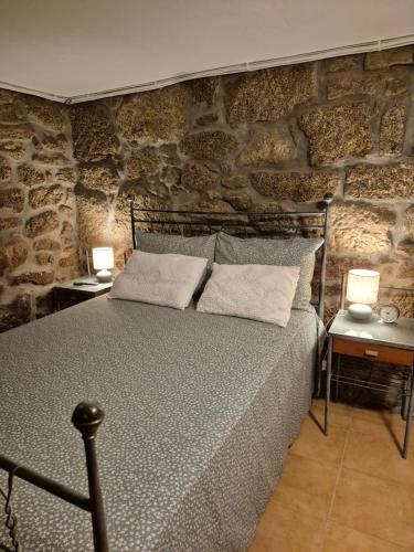 een bed in een kamer met een stenen muur bij Casa das Pédrinhas Pousade Guarda in Guarda