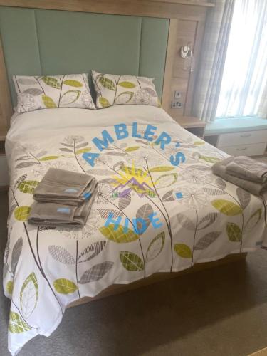 a bed with a white comforter with a flower pattern at Amblers Hide, Brigham, Cockermouth, Cumbria in Cockermouth