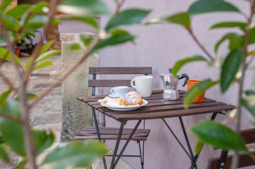 a table with a plate of food and cups on it at Pura Apartment Hill View Stay near Peccioli & Lajatico in Palaia