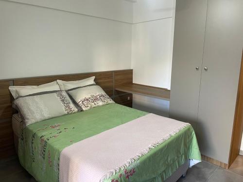 a bedroom with a bed with a green comforter at Refúgio central in Barbacena
