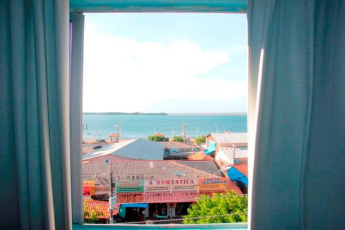 a window with a view of a building and the ocean at Grand Center Hotel in Santarém