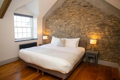 een slaapkamer met een groot bed en een stenen muur bij Gelli Genlas Aberaeron in Synod