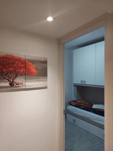 Un cuadro de un árbol en una pared al lado de un dormitorio. en Appartamento a MXP Aeroporto-Via Mameli, en Somma Lombardo