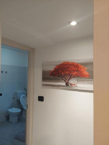 Un cuadro de un árbol en un baño con inodoro. en Appartamento a MXP Aeroporto-Via Mameli, en Somma Lombardo