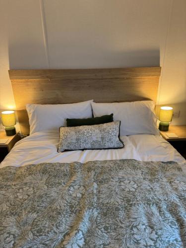 a large white bed with two pillows and two lamps at 28 Fentley Green - Ashbourne Heights Holiday Park in Fenny Bentley