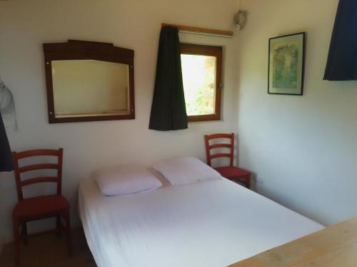 a bedroom with a bed and two chairs and a mirror at La vie en Rosans - The upperhouse in Saint-André-de-Rosans