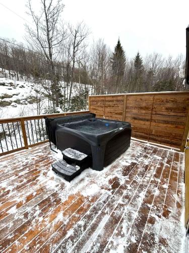 a hot tub sitting on a deck in the snow at Nature & Breathtaking View - Le Dumont - B in Saint-Philémon