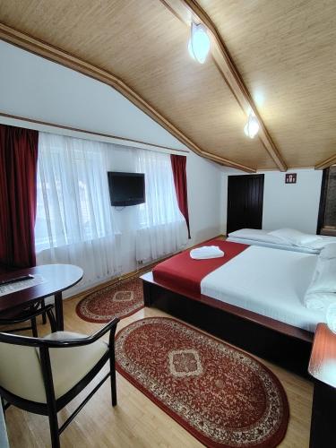 a bedroom with two beds and a table and a tv at Vila Bratocea in Cheia