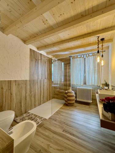 a bathroom with wooden walls and wooden floors and a large window at Chalet il pino in San Bernardo