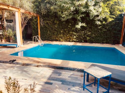 uma piscina com uma mesa e uma cadeira ao lado em Riad Eglantine em Touggana