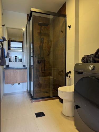 ein Bad mit einer Dusche und einem WC sowie ein TV in der Unterkunft Black Chic Studio in Cochabamba