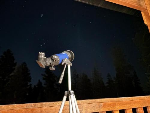 a telescope on a tripod in front of a window at Brand New Cabin with Fire Pit & Outdoor Projector in Duck Creek Village