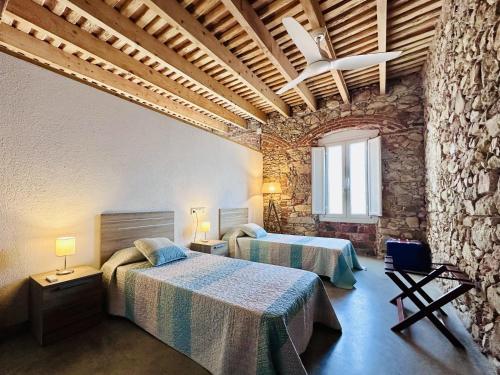 een slaapkamer met 2 bedden en een stenen muur bij Can Sala CostaBravaSi in Santa Cristina d'Aro