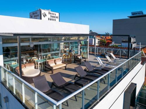 uma varanda com cadeiras e mesas num edifício em Bossa Jurerê Hotel em Florianópolis