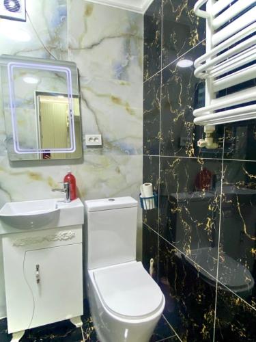 a bathroom with a white toilet and a sink at Апартамент Плаза 3 in Shymkent