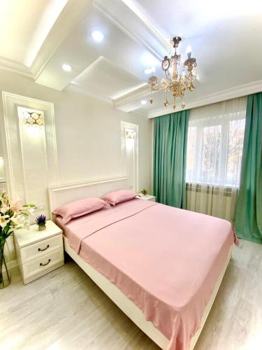 a bedroom with a pink bed and a chandelier at Апартамент Плаза 3 in Shymkent