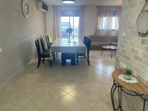 een eetkamer met een tafel, stoelen en een bank bij מנוחה ומרגוע in Tiberias