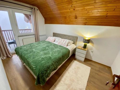 a bedroom with a bed with a green blanket at Cavljak Retreat, Sarajevo in Barice