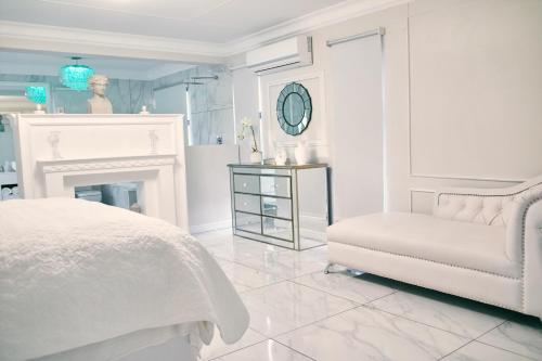 a white bedroom with a white bed and a chair at WINDHOEK ODYSSEY House in Windhoek
