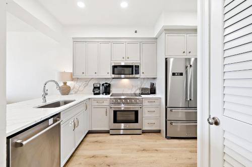 uma cozinha com armários brancos e eletrodomésticos de aço inoxidável em HP 42W Peaceful Nest by 30A Escapes em Rosemary Beach