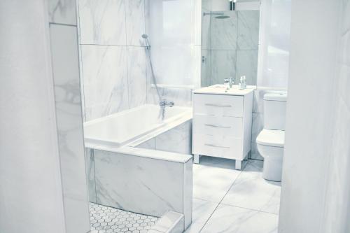 a white bathroom with a tub and a toilet at WINDHOEK ODYSSEY House in Windhoek