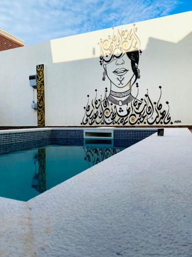 a painting on the side of a building with a pool at Villa Sabrina in Awlād ‘Umar