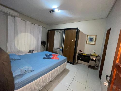 een slaapkamer met een bed met een blauwe deken en een bureau bij Suítes Privativas - Casa Compartilhada in São Raimundo Nonato