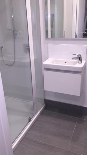 a white bathroom with a sink and a shower at Bucklands Beach Waterfront Motel in Auckland