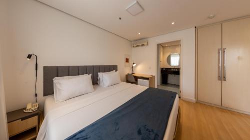 a bedroom with a large white bed with a telephone at St Charbel by Charlie in São Paulo