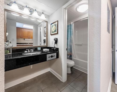 Relaxing Oceanfront Condo - Holiday Pavilion 211 في ميرتل بيتش: حمام مع حوض ومرحاض ومرآة