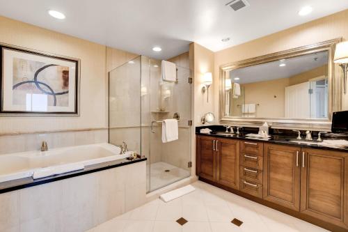 a bathroom with a tub and a shower and a sink at The Signature at MGM Grand by Owners Direct in Las Vegas