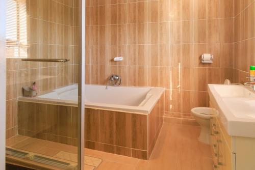 a bathroom with a tub and a toilet and a sink at Comfort B&B in Bulawayo