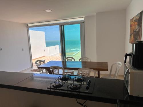 uma cozinha e sala de jantar com vista para o oceano em Suite numero 3 BEIRA MAR com ar condicionado , cozinha compartilhada e completa com Micro ondas air fryer forno elétrico fogão Geladeira freezer gelagua e cafeteria elétrica Tudo para vc se sentir em casa além de um Deck com churrasqueira vista mar em Icapuí