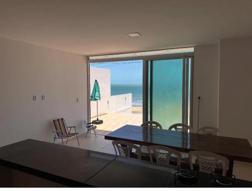 uma sala de jantar com uma mesa e vista para o oceano em Suite numero 3 BEIRA MAR com ar condicionado , cozinha compartilhada e completa com Micro ondas air fryer forno elétrico fogão Geladeira freezer gelagua e cafeteria elétrica Tudo para vc se sentir em casa além de um Deck com churrasqueira vista mar em Icapuí