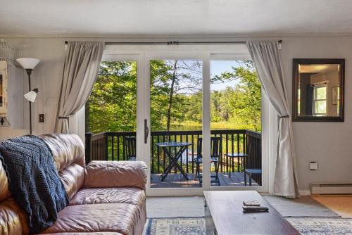 un salon avec un canapé et un balcon dans l'établissement Little Longbow Lakefront Chalet, à Becket