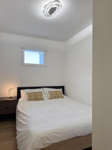 een slaapkamer met een bed met witte lakens en een raam bij Torrent House in Bouveret