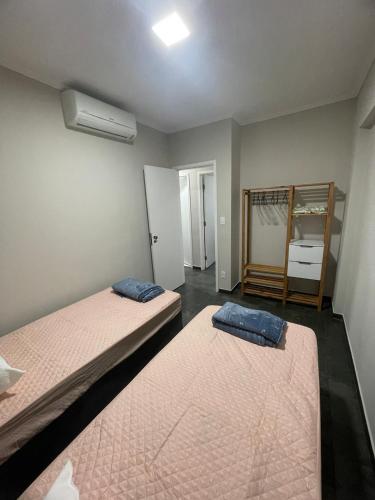 a room with two beds and a room with a mirror at Apto pe na areia 3 dorm ar cond in Caraguatatuba