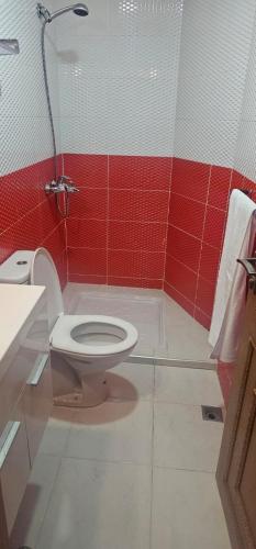 a bathroom with a toilet and a red wall at Atlas stay in Fez