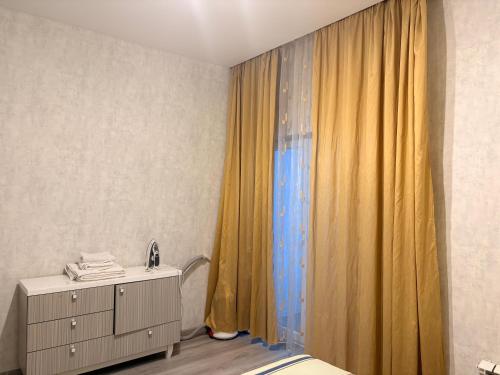 Apple city في Prigorodnyy: غرفة نوم بسرير وستارة صفراء