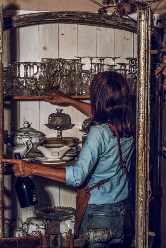 a woman is reaching into a shelf of dishes at B&B CUCUTÍ in Ziano Piacentino