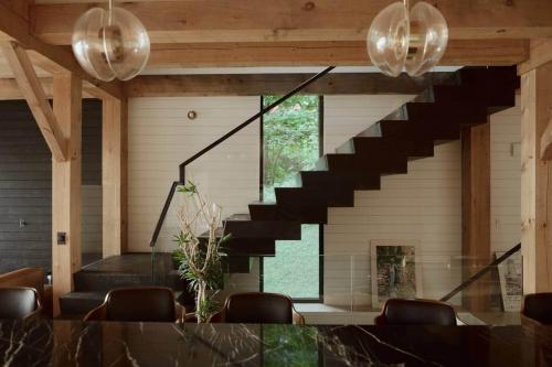 a living room with a staircase and a table and chairs at Shatemuc, a magical getaway on the Hudson River in Kingston
