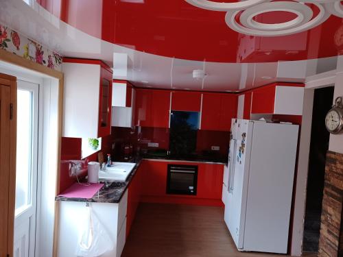 a kitchen with red cabinets and a white refrigerator at Room in Northampton in Great Billing
