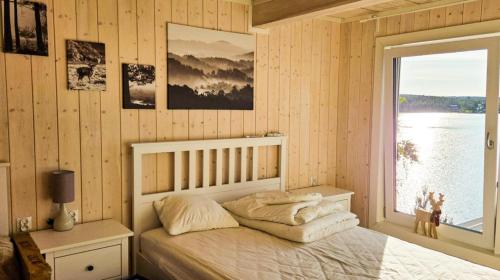 ein Schlafzimmer mit einem Bett und Blick aufs Wasser in der Unterkunft Harnas in Säffle