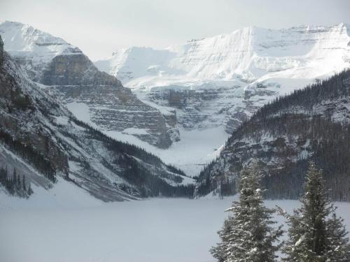 a snow covered mountain with a lake in the foreground at Valemount Vacation Inn in Valemount