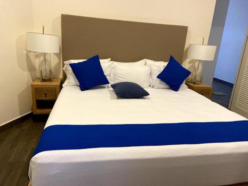 un grande letto con cuscini blu e bianchi di VIVO 2 Bedroom Ocean Front Condo 180 degree ocean views a Puerto Escondido
