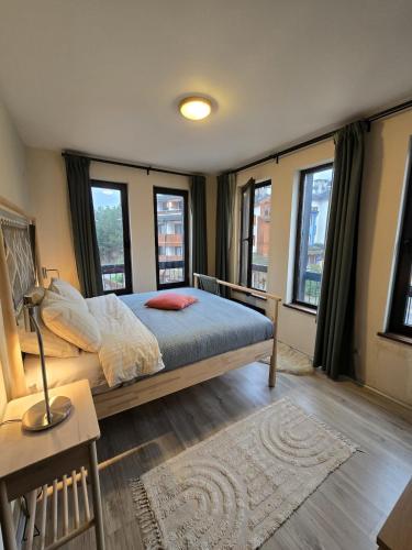 a bedroom with a bed with windows and a rug at Tranquility Apartment Pirin Golf in Razlog