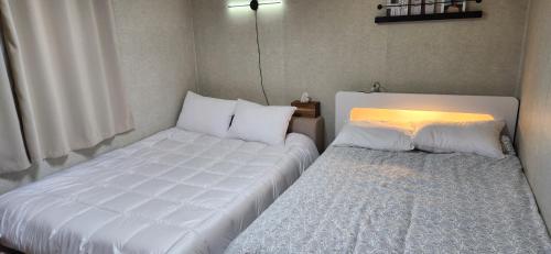 two beds in a small room with a bedskirts at Manu Stay in Seoul