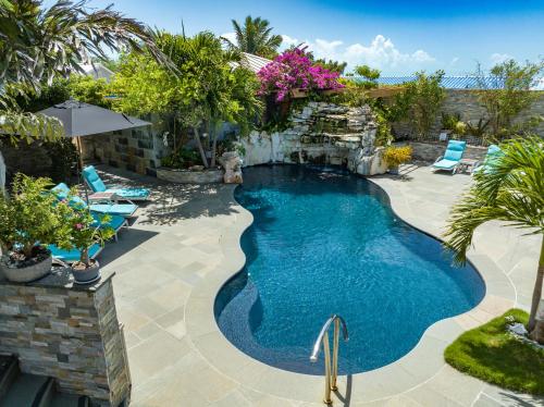 Kokomo Botanical Resort - Caribbean Family Cottages في ترتل كوف: مسبح في ساحة فيها كراسي واشجار