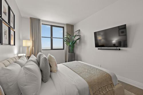 蒙特朗布朗Tremblant Prestige - Horizon 2-204的白色卧室设有一张床和墙上的电视