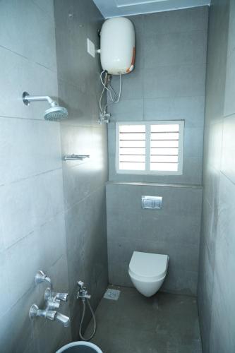 a bathroom with a toilet and a sink and a window at Brown Spring Home Stays in Thanjāvūr